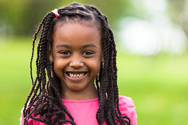 Portrait of cute smiling black girl in pink outdoors Outdoor close up portrait of a cute young black girl smiling - African people little black girl hairstyle stock pictures, royalty-free photos & images