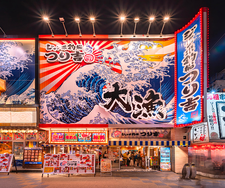 osaka, japan - dec 04 2022: Fish and seafood restaurant Jumbo Tsuribune Tsurikichi with a  giant placard on facade depicting sea waves evocating The Great Wave of the Ukiyo-e master Katsushika Hokusai