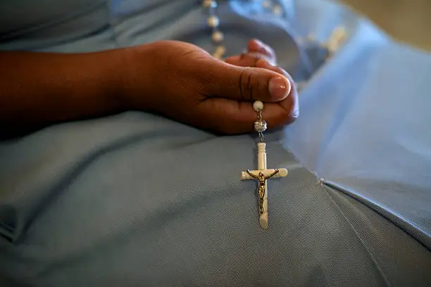 People and religion, catholic sister praying in church and holding cross in hands. With model release