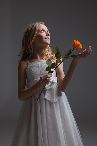 Girl giving rose for mother's day, birthday or valentine's day. Isolated on dark background.