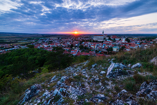 This photograph captures the mesmerizing sunset over the Czech town of Mikulov. The partially cloudy sky, taken with a narrow aperture to create the signature sunburst effect, provides an enchanting backdrop. Below, the town's panorama unfolds, crowned by the prominent silhouette of the castle. This image is a testament to the elegance of Mikulov's evenings