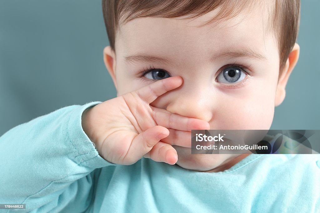 Close up of baby looking at camera with blue eyes Close up of a baby girl looking at camera with a big blue eyes with a green unfocused background Baby - Human Age Stock Photo