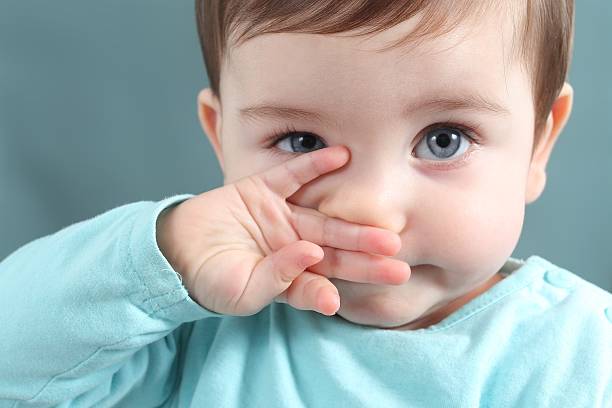 Close up of baby looking at camera with blue eyes Close up of a baby girl looking at camera with a big blue eyes with a green unfocused background nose stock pictures, royalty-free photos & images