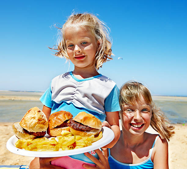 Child eating fast food at beach outdoor.