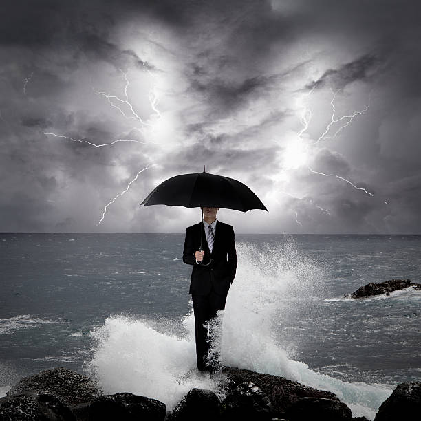 uomo d'affari sotto un ombrello in mare - sea waving wave thunderstorm foto e immagini stock
