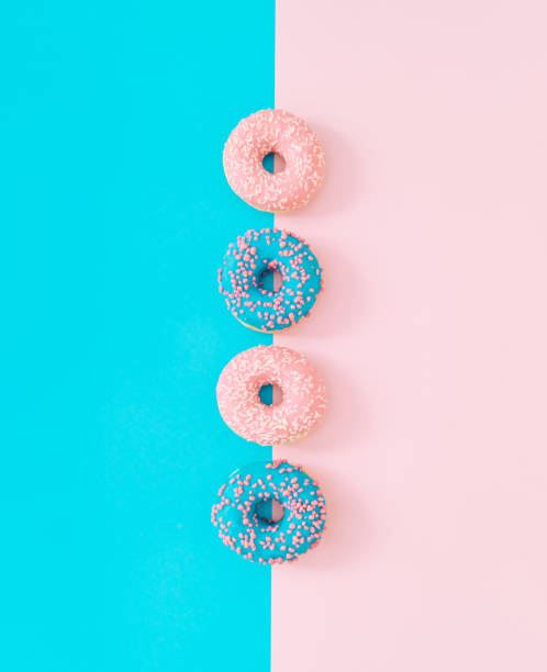 istock Pink and blue glazed donuts on light blue and pastel pink background. Creative concept. Minimal delicious food idea. Flat lay yummy donut composition. Donuts aesthetic. 1784496429