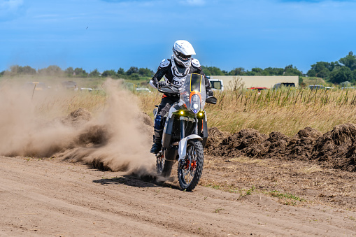 Male motocross rider racing in dust, rear view