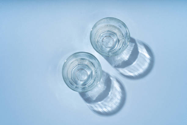 istock Two glasses for drinks, a long shadow from the sun on a light blue background. 1784502284