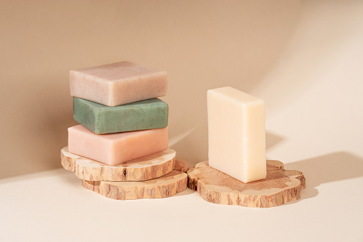 Pattern natural handmade soap of different sizes and colors. Brown background shadows of flowers from the sun. Cosmetic pedestal for product promotion
