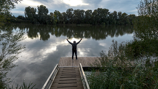 Lone man is euphoric on a wooden dock in a natural setting, outdoors, water river space, lone man in a rural setting, on an autumn day, Tordesillas Valladolid, Spain