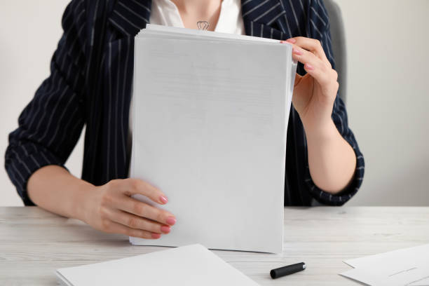 istock Woman stacking documents at white wooden table in office, closeup 1784517798