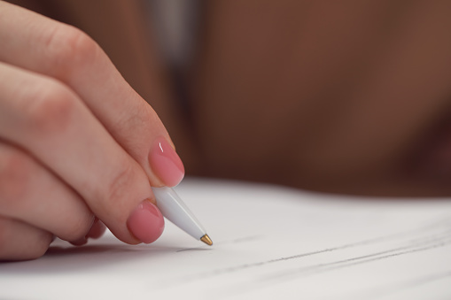 Woman signing documents at table in office, closeup. Space for text