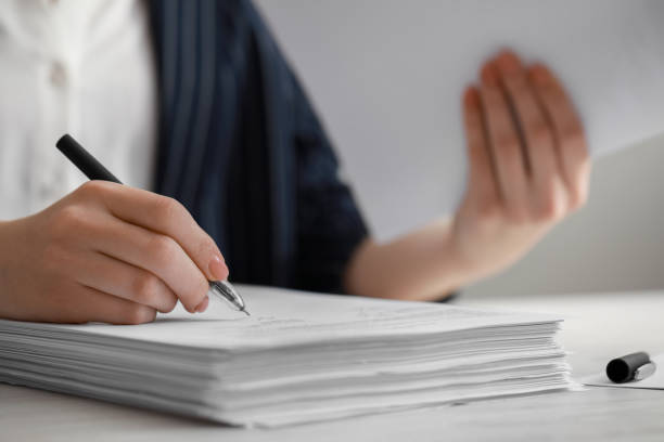 istock Woman signing documents at white wooden table in office, closeup. Space for text 1784519459