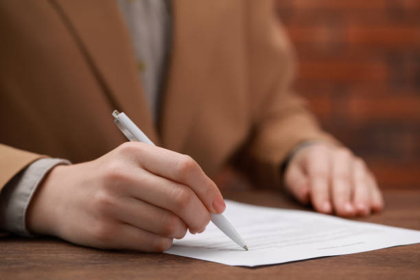 istock Woman signing documents at wooden table in office, closeup. Space for text 1784519462