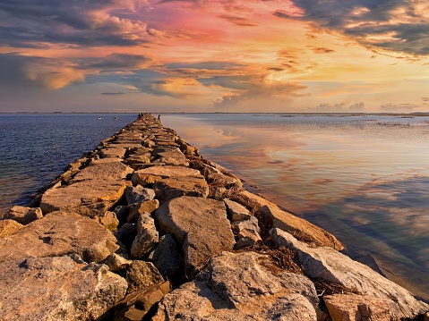 Warm sunset along jetty causeway from Provincetown towards the Wood End lighthouse. A popular spot for recreational boaters, swimmers and fisherman just west of Provincetown Massachusetts. The boulders extend out some 1/2 mile to the outer islands at the tip of the Cape.
