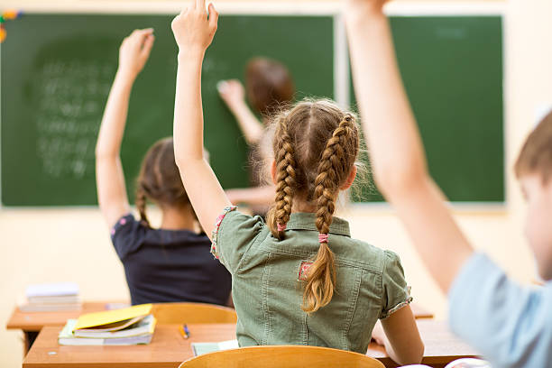 istock Schoolchildren raising hands in classroom 178453529