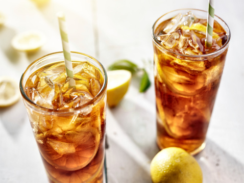 close up photo of two cold glasses of iced tea with lemons. Shot with selective focus.
