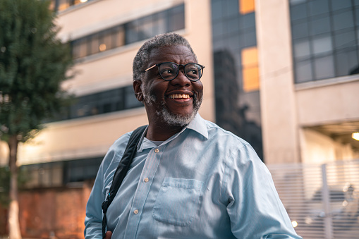 Mature black man wearing glasses smiling on the street
