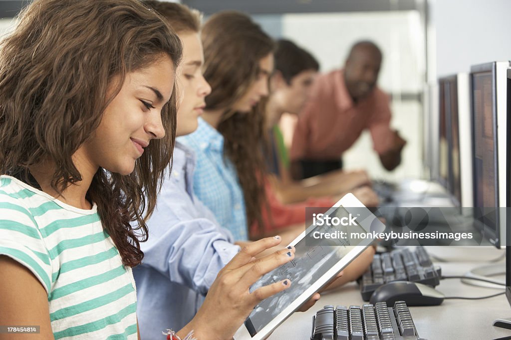 Girl Using Digital Tablet In Computer Class Girl Using Digital Tablet In Computer Class Sitting Down Concentrating Education Stock Photo