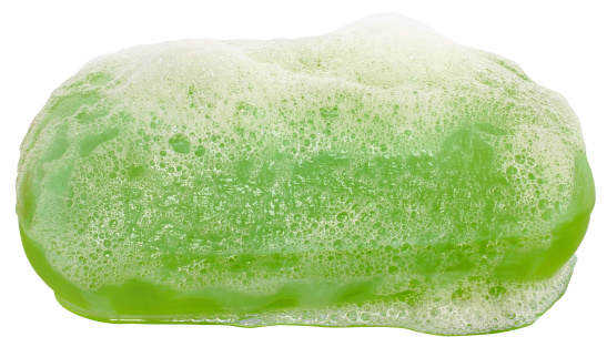 Bar of green soap in the foam close up on white background.