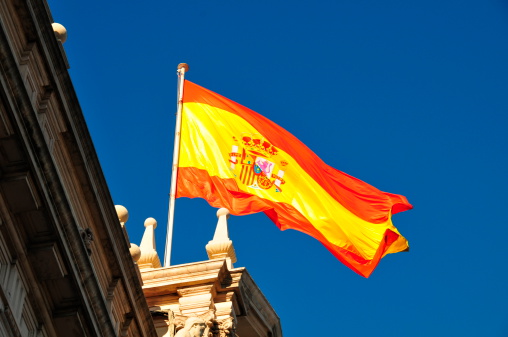 Spanish flag on the sunny day against dark blue sky