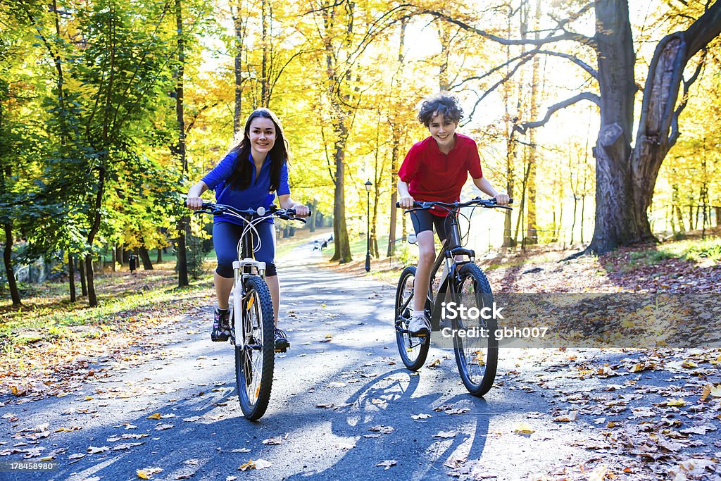 Fille et garçon équitation vélos dans le parc de la ville - Photo de 14-15 ans libre de droits