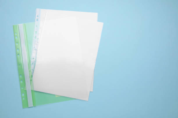 File folder with punched pockets and paper sheets on turquoise background, top view. Space for text