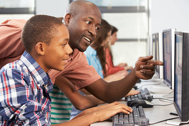 professor ajudar os alunos trabalhando em computadores em sala de aula - computer lab computer people computer monitor - fotografias e filmes do acervo