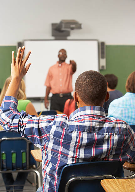 Male Pupil Raising Hand In Class Male Pupil Raising Hand In Class Answering Question hand raised classroom student high school student stock pictures, royalty-free photos & images