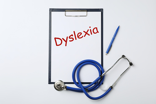 Clipboard with word Dyslexia, pen and stethoscope on white background, top view