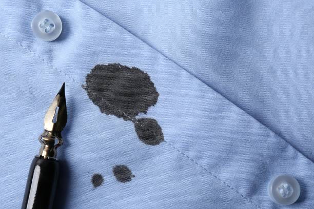 istock Black ink stain on light blue shirt and pen, top view. Space for text 1784602127