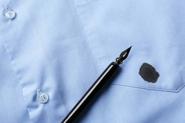 istock Black ink stain on light blue shirt and pen, top view. Space for text 1784602664