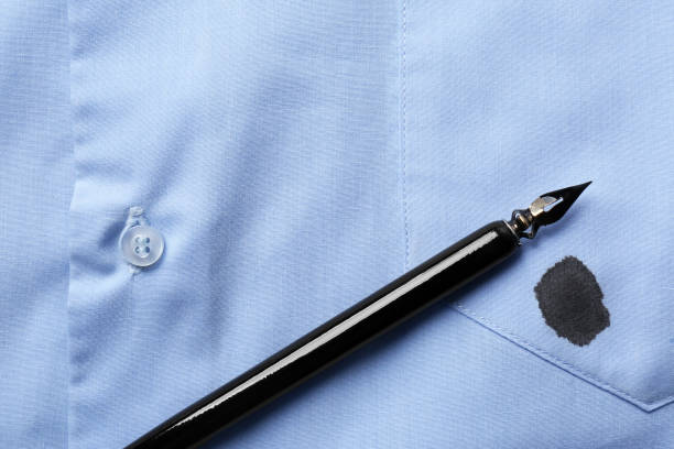 istock Black ink stain on light blue shirt and pen, top view. Space for text 1784602671