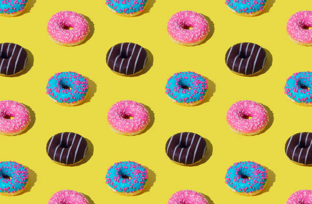 istock Creative pattern of colorful donuts on light yellow background. Minimal concept. Trendy donuts pattern background. Yummy food composition. Donuts aesthetic. 1784602978