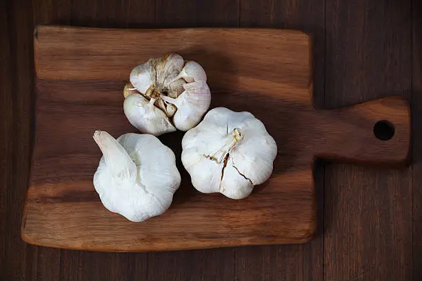 Photo of Garlic bulbs on the wooden cutting board