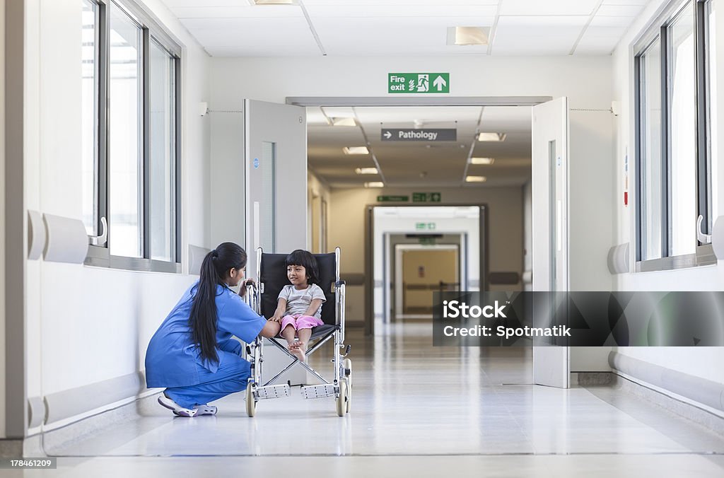 Female Girl Child Patient in Wheelchair & Hospital Nurse Young female child patient in wheelchair sitting in hospital corridor with Indian Asian female nurse Child Stock Photo