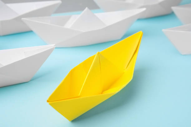 istock Yellow paper boat among others on light blue background, closeup. Uniqueness concept 1784612619