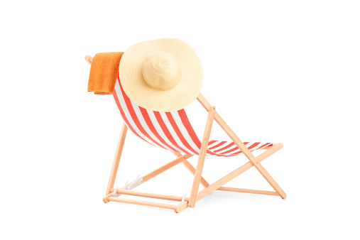 Towel and hat on a sun lounger with stripes, isolated on white background