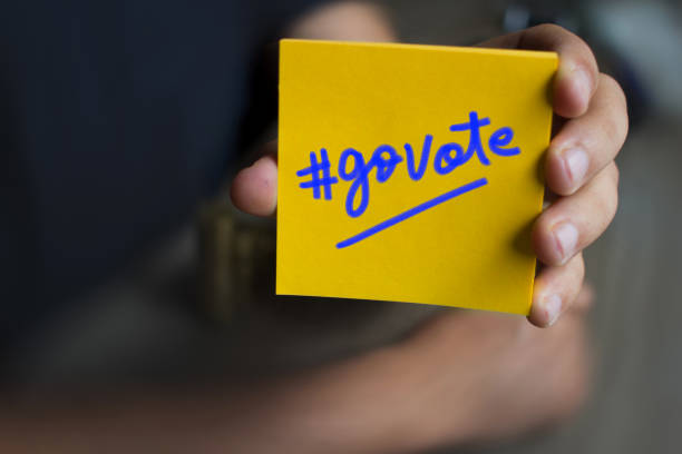 Hand holding a yellow Paper with the word GoVote