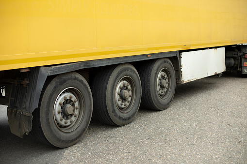Wheels of truck. Large trailer wheels. Yellow truck trailer. Transport details.