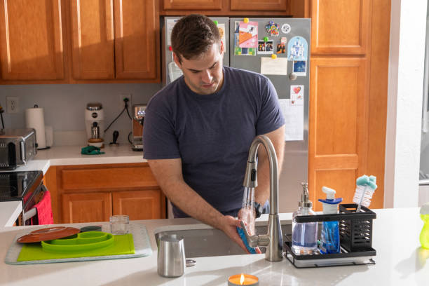 istock Young man washing dishes in the kitchen 1784637784