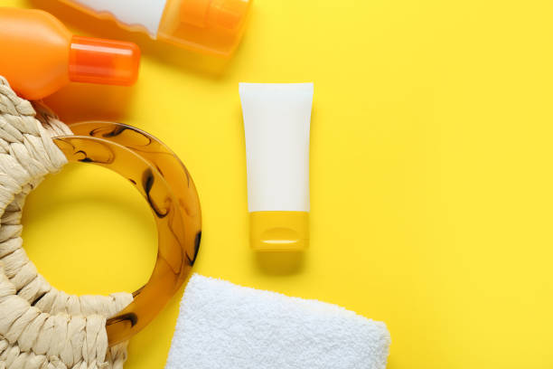 istock Suntan products, terry towel and bag on yellow background, flat lay. Space for text 1784639336