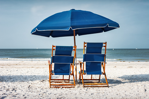 Beach with two Lounge Chairs and Umbrella in Fort Myers, Florida, USA.