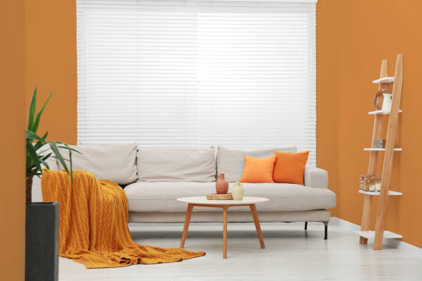 istock Stylish sofa and coffee table in room with orange walls. Interior design 1784654094
