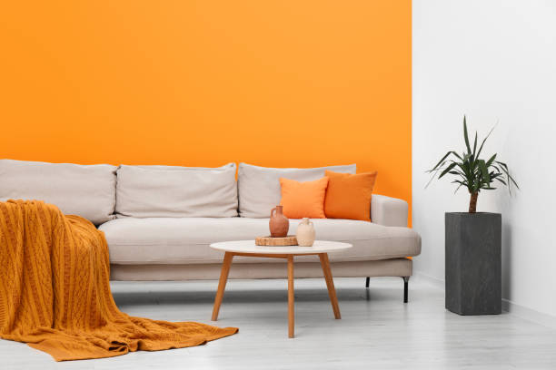 istock Stylish sofa and coffee table in room with orange walls. Interior design 1784654697
