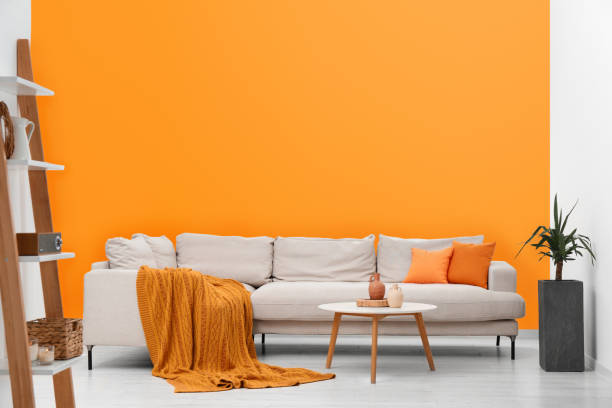 istock Stylish sofa and coffee table in room with orange walls. Interior design 1784654701
