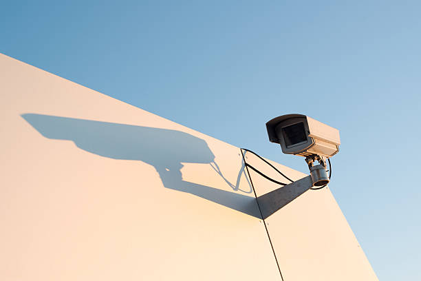 Security camera on a bright metal wall against great blue sky with room for your copytext