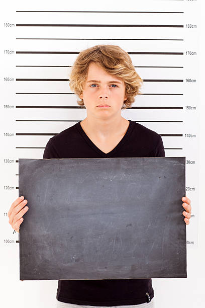 nastoletni chłopiec trzyma tablica przyjmowania przestępca kubeczek spłynął - mug shot arrest blackboard prison zdjęcia i obrazy z banku zdjęć