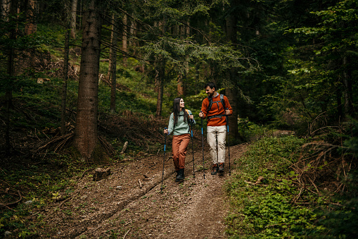 Couple on a wooded trail with backpacks and hiking poles