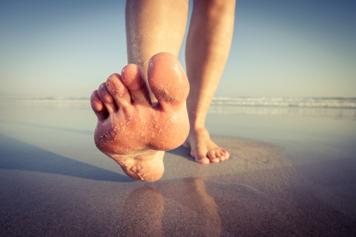 Female walking on beach barefoot.